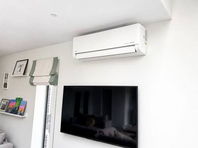Wall-mounted indoor air conditioning unit installed above a television in a living room