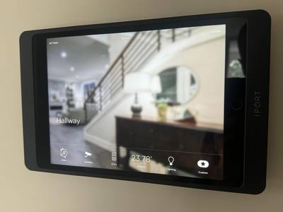 Wall-mounted smart home control panel showing rooms, scenes and camera feeds